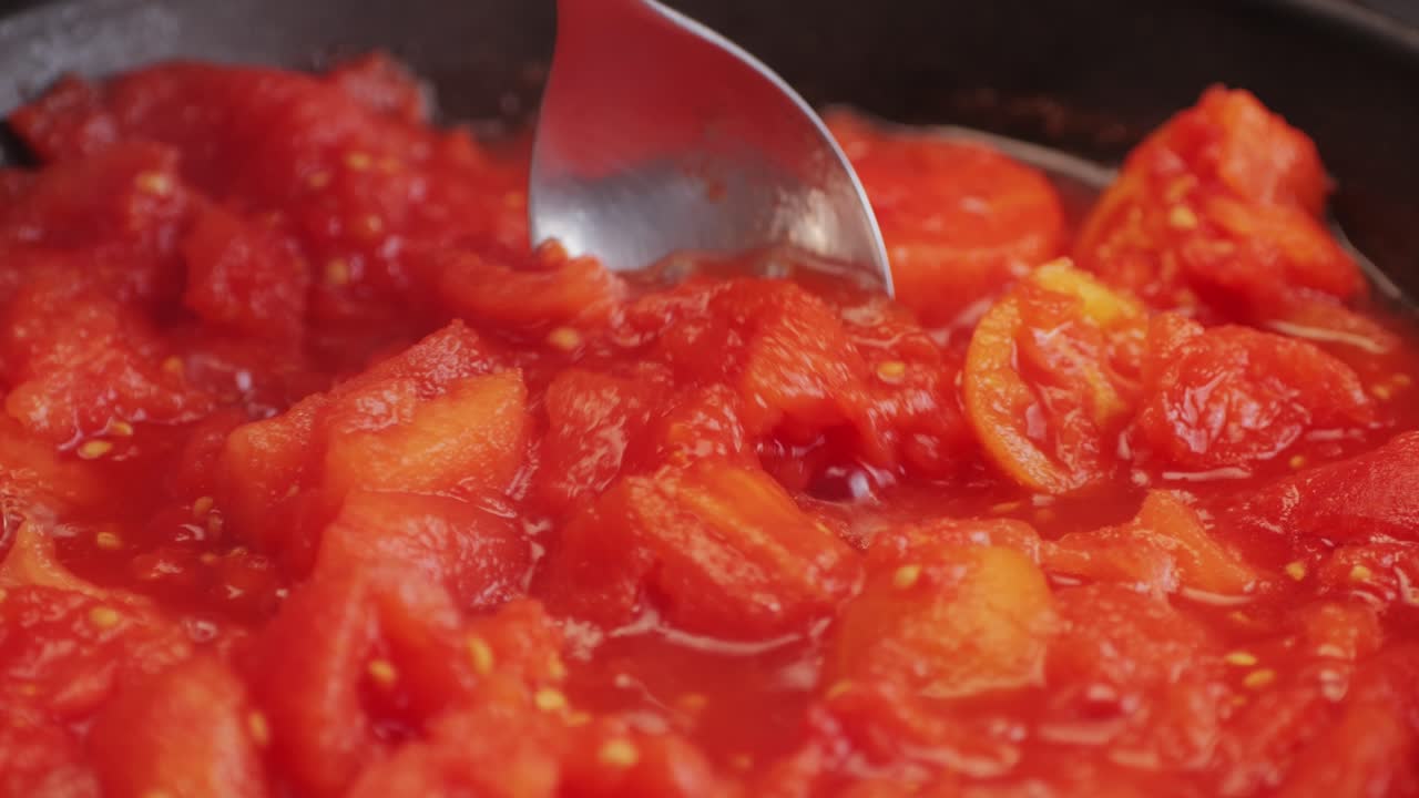 Cooking fresh peeled canned tomato Juice sauce with mozzarella cheese in pan, peeled tomatoes boiling in their own juice, making tomatoes pasta sauce .Top view close up, Italian traditional cuisine food.