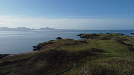 aerial view peaceful ynys llanddwyn island with hazy snowdonia mountain range across shimmering irish sea at sunrise