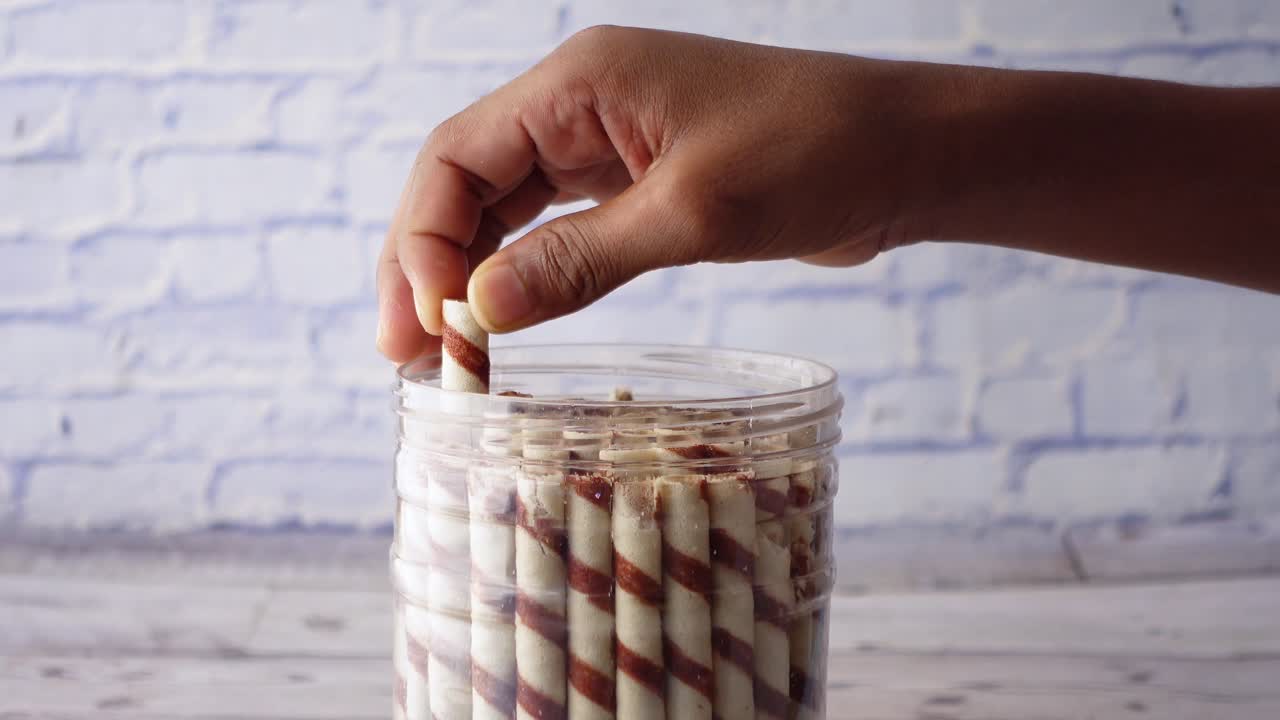 컨테이너에서 초콜릿 웨이퍼 스틱을 손으로 가져가는 것