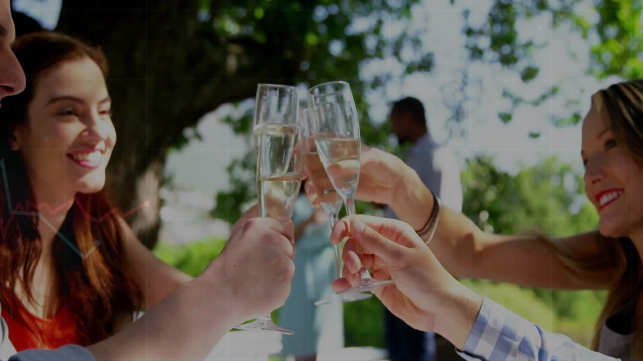 Raising seated friends as hands join clinking champagne flutes under tree, red top and plaid shirt