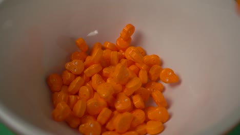 Extreme-close-up-of-orange-skull-shaped-candy-falling-on-a-white-plate