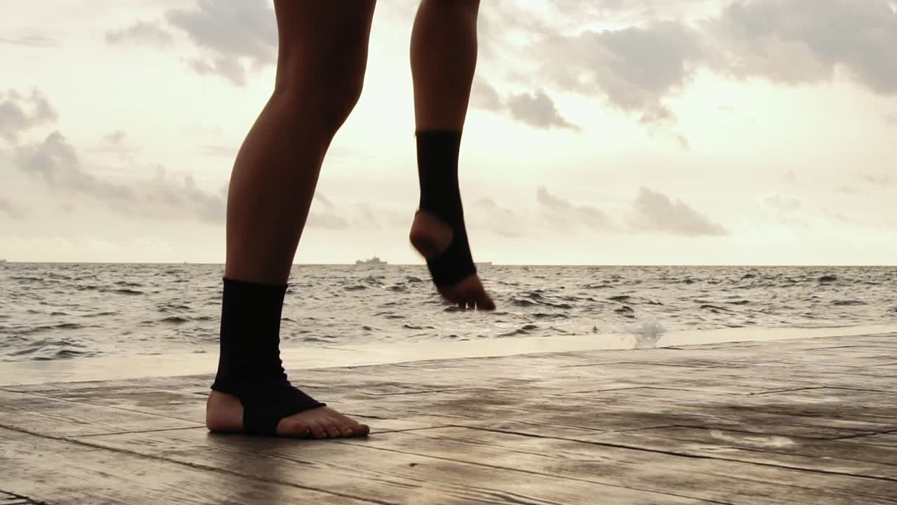 High pace video: Female boxer's legs moving on during the training. Woman is training by the beach. Close Up on legs