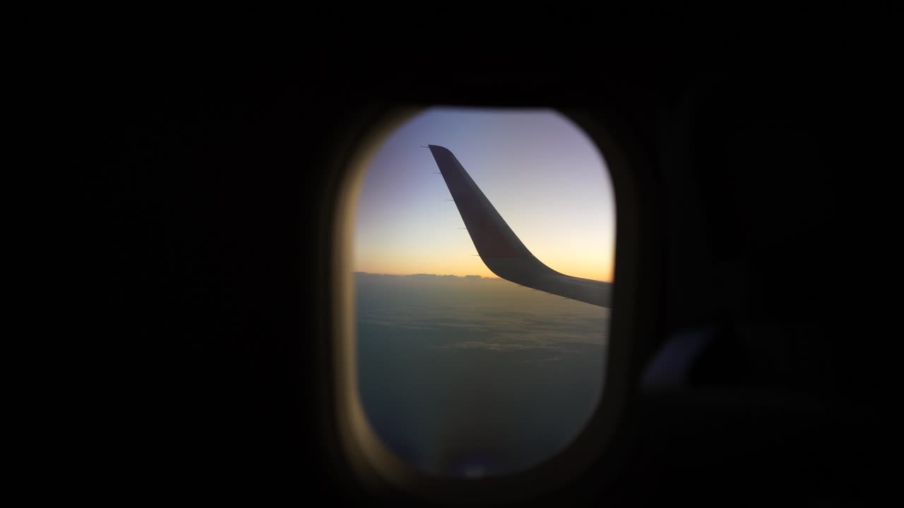 Airplane's left wing seen through the airplane window from the passenger's perspective