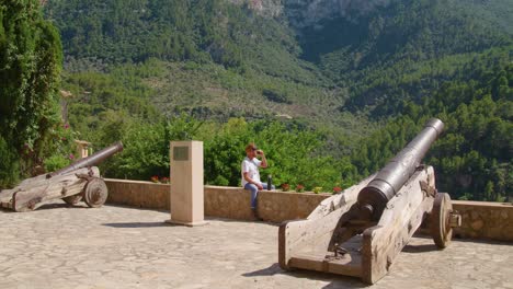 male traveler resting and drinking coffee on ancient cannon