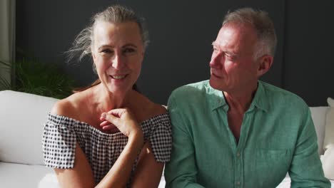 portrait of caucasian senior couple talking while having a video call at home