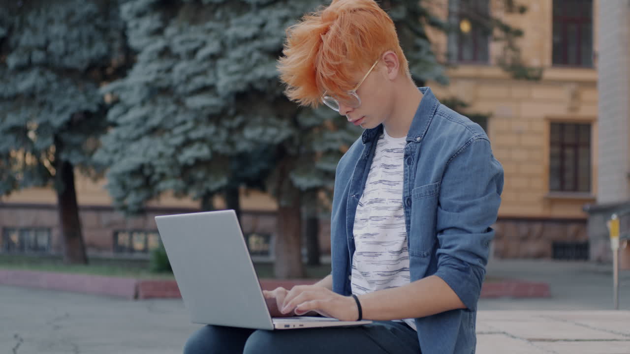 Teenager working on a laptop outdoors