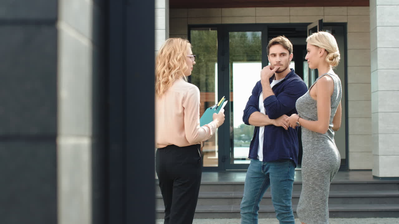 젊은 부부가 함께 고급 주택을 구입하고 있습니다. 부동산 에이전트가 부부에게 주택을 조언하고 있습니다.