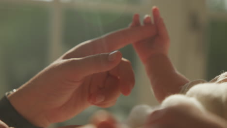 tender moment between mother and newborn holding fingers