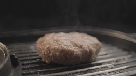 beef or chicken burger meat on grill being prepared for a delicious burger sandiwich , with a black background and simple light set up shot on raw 4k