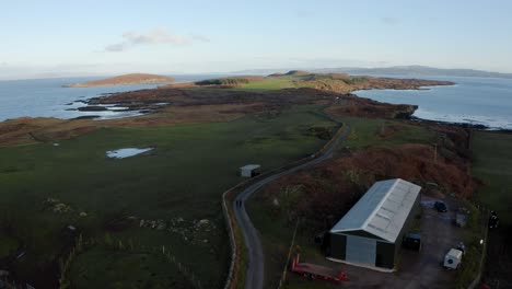 Aéreo---Hermoso-Horizonte,-Un-Almacén-Y-Una-Carretera,-Isla-De-Gigha,-Kintyre,-Escocia