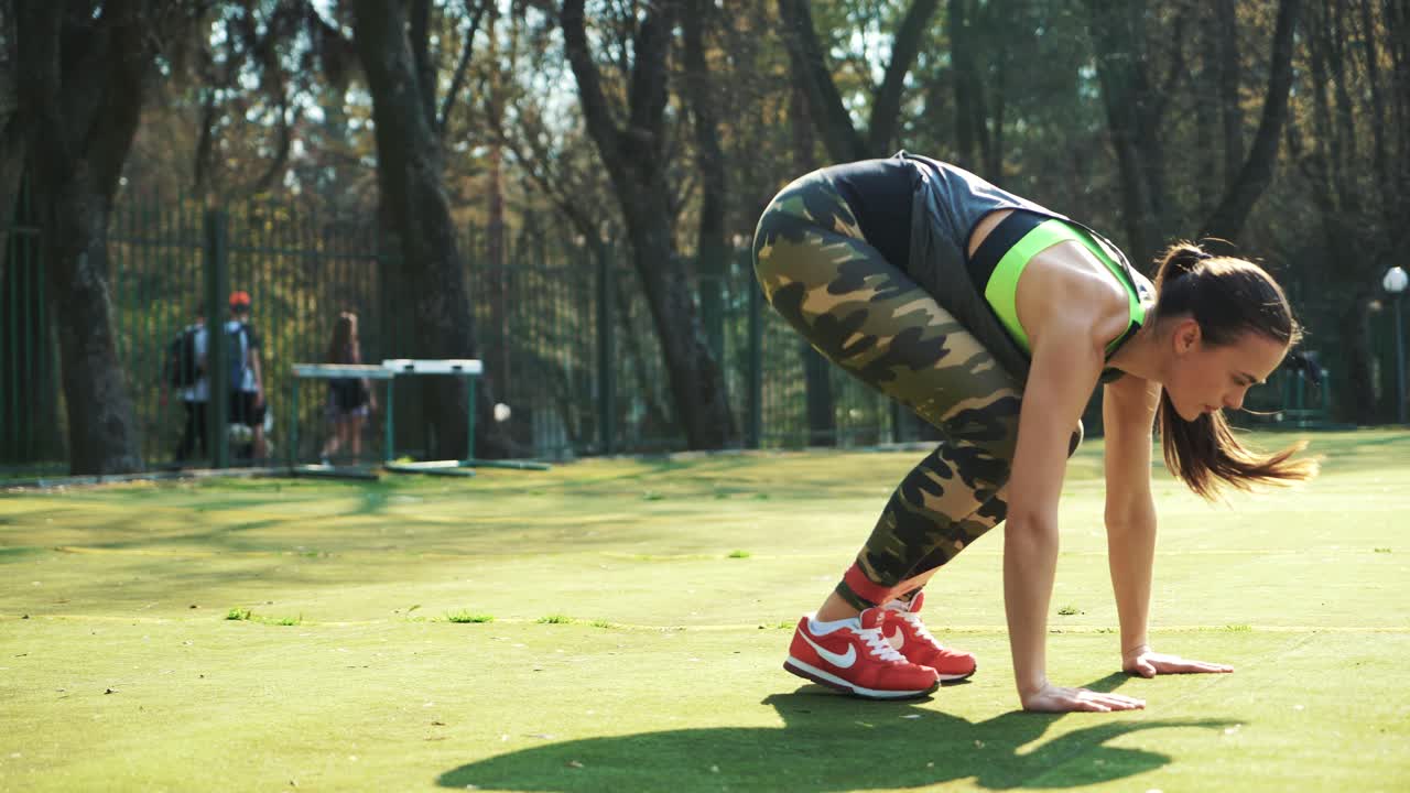 Fitness women training with sport expander in the stadium. Active girl doing leg muscle exercises. Healthy lifestyle.