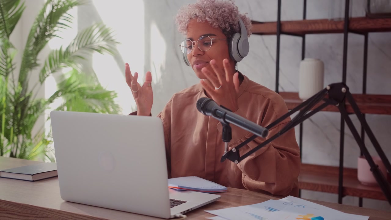 Smiling african woman wearing wireless headphones preparing to record podcast