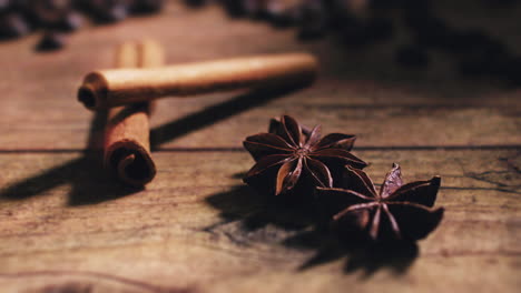 Camera-moving-away-from-cinnamon-and-star-anise-with-coffee-beans-in-the-back-on-a-wooden-table