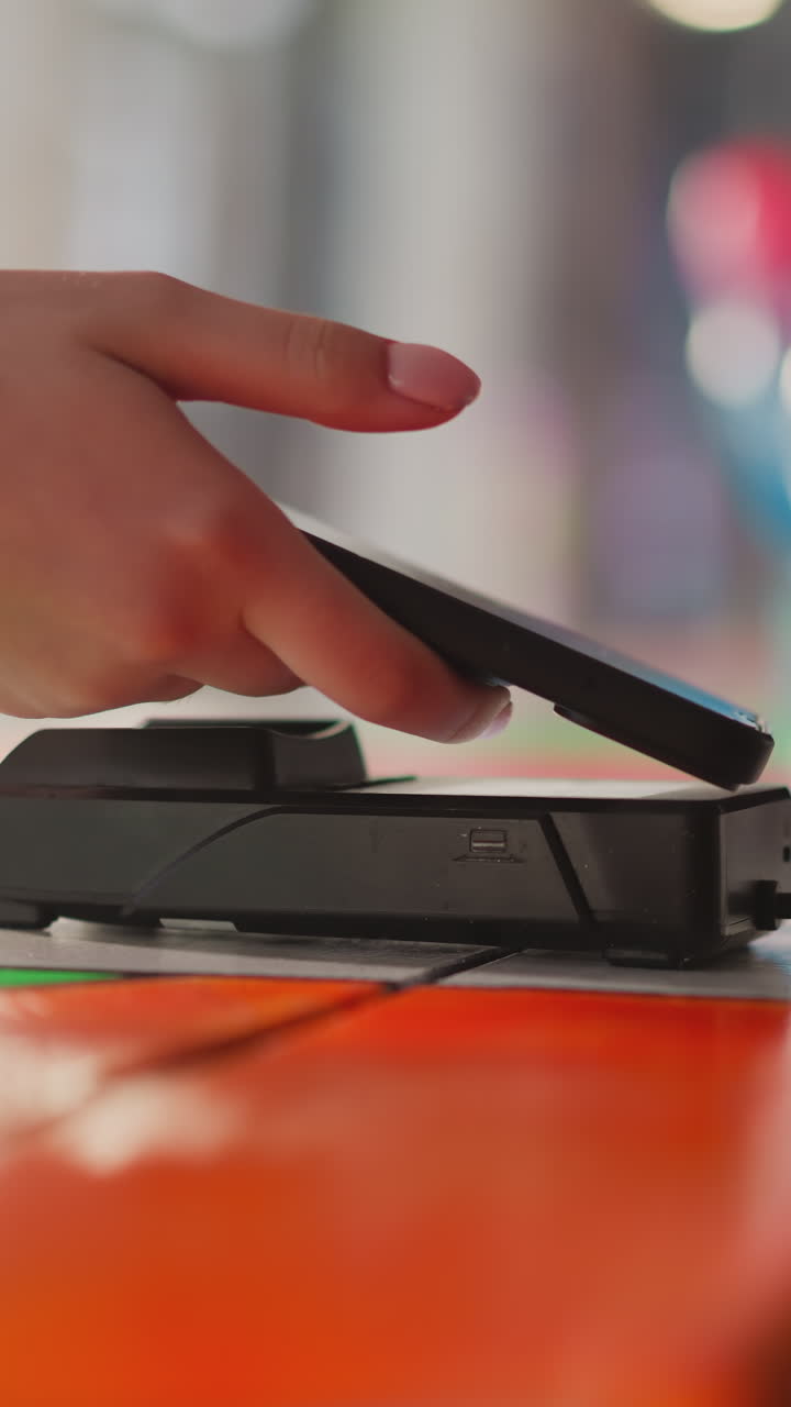 mujer toca la terminal pos con el teléfono móvil en la tienda de primer plano. el cliente utiliza la tecnología de pago digital para comprar bienes en la tienda. servicio bancario