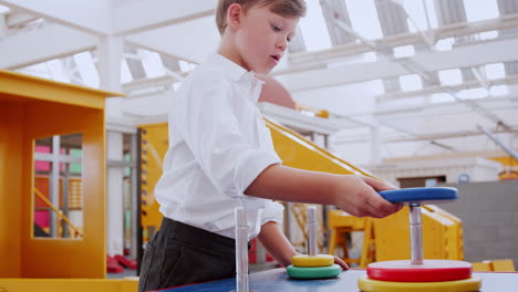 young white boy building ring tower puzzle at science centre