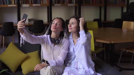 Young-Female-Students-Sitting-On-Sofa-At-Library-Or-Workplace