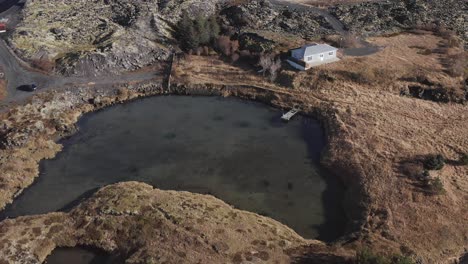 pequena cabana com cais privado no lago na paisagem da islândia, aérea