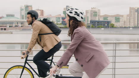 american man and woman riding bikes and talking to each other while going to work