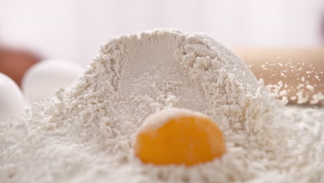 egg yolk falling and rolling down the pile of white flour in slow motion