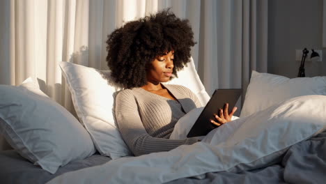 woman relaxing in bed with a tablet