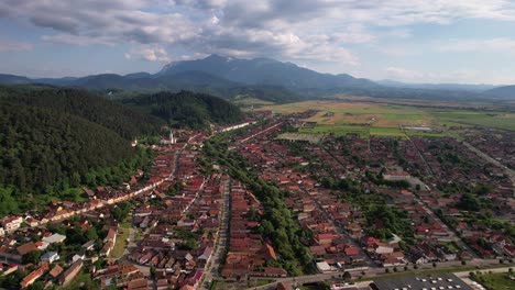 Ciudad-De-Rasnov-Con-Telón-De-Fondo-De-Las-Montañas-De-Bucegi,-Día-Soleado,-Vista-Aérea