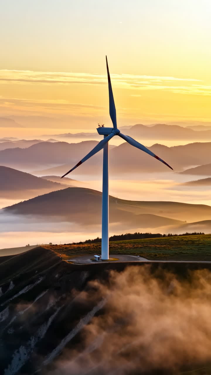 Wind Turbine at Sunrise over Foggy Mountains