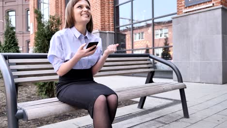mujer celebrando el éxito mientras está al aire libre usando un teléfono inteligente