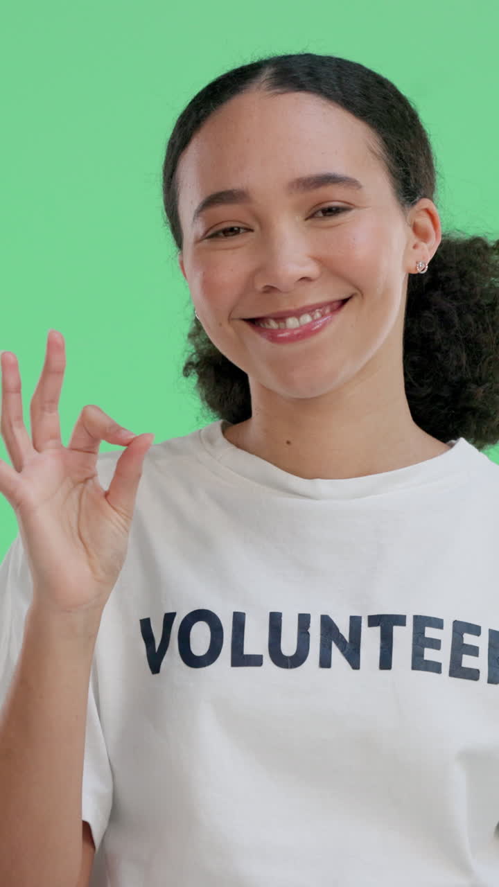 Donna volontaria sorridente che fa il gesto "OK" su schermo verde