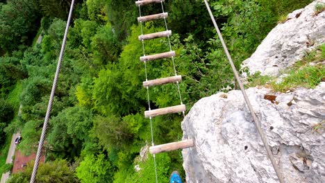 am man walking on a suspension bridge made out of pieces of wood