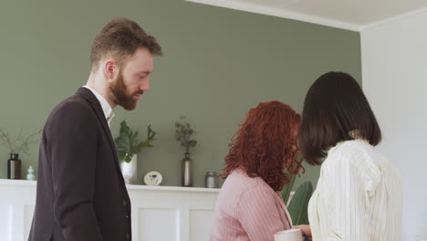 young redhead woman showing paper report to her two multiethnic colleagues and debating together