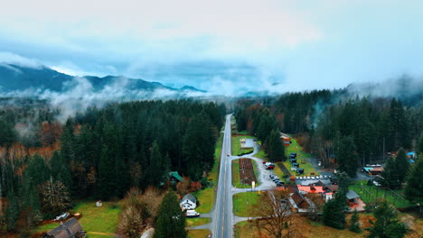 following the car riding by the straight highway across the mount rainier national park in washington state, the usa. top view on some recreational area with cottages around the road. thin mist rises in the air.