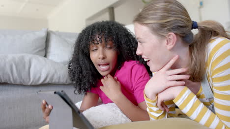amigas adolescentes felices y diversas hablando y usando tableta en casa, en cámara lenta