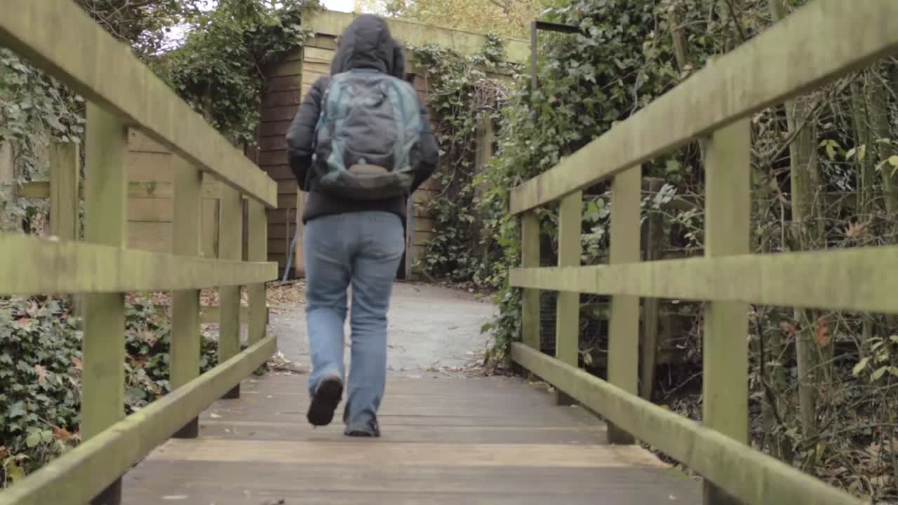 Hiker crosses wooden bridge to bird hide