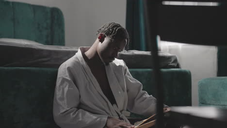 man in white robe sitting on floor, focused on sipping tea in peaceful bedroom. soft sunlight filters through window, creating a calm and tranquil atmosphere, perfect for a moment of relaxation