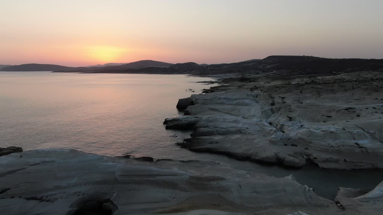 vista de avión no tripulado en grecia volando sobre una zona de roca blanca en forma de luna en la isla de milos al amanecer junto al mar azul oscuro