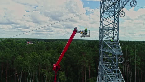 high voltage electrician on a crane with mobile elevating work platform to inspect a pylon