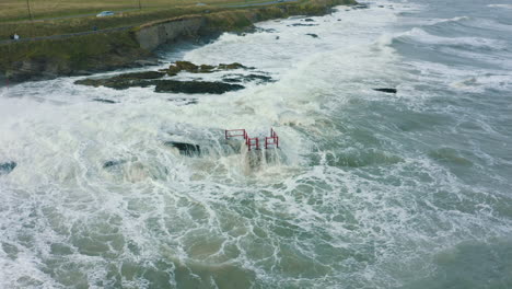 Aerial-view-of-waves-crashing-against-rocks-along-the-coastline-during-a-storm