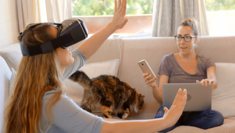 una pareja de lesbianas usando auriculares de realidad virtual y portátil en la sala de estar 4k