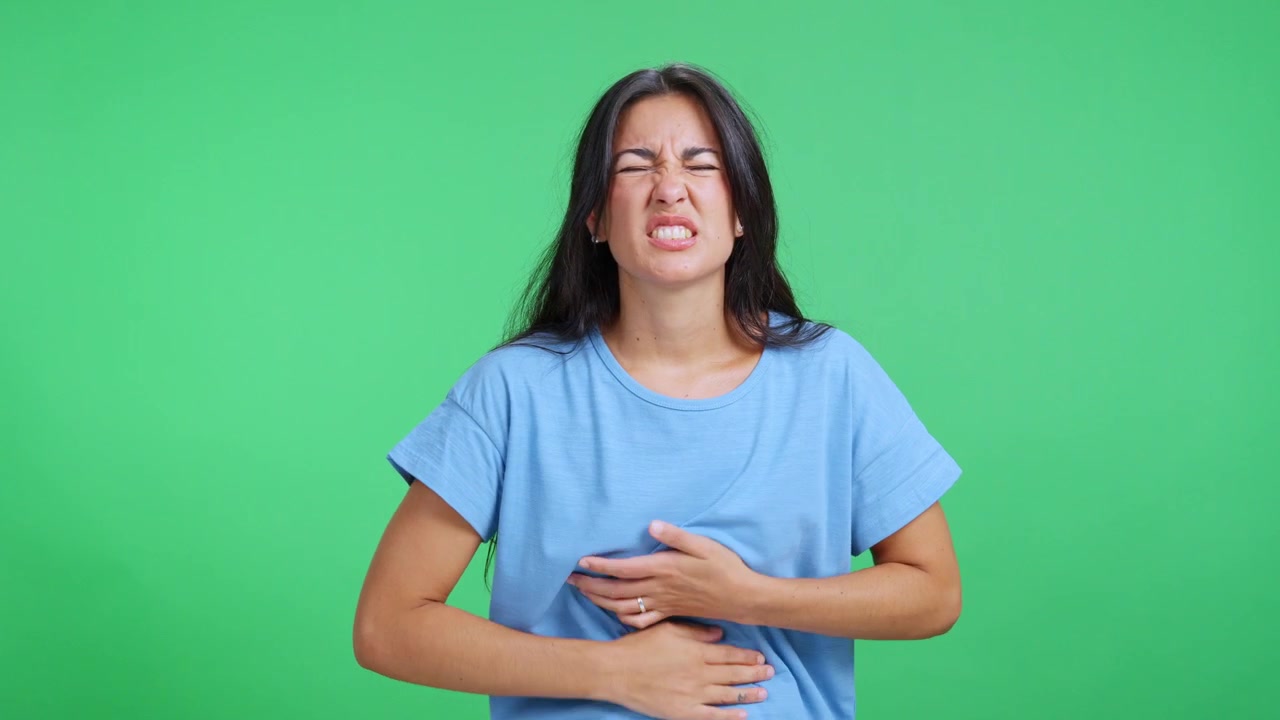 Giovane donna che prova un forte dolore addominale su schermo verde