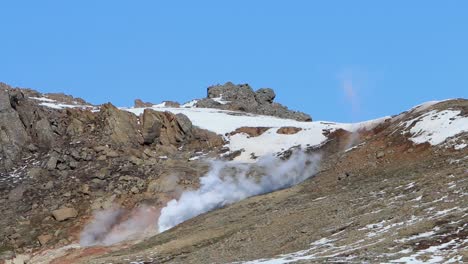 steam rising from geothermic activity on a mountainside in early spring