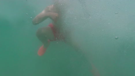 young boy jumping from pontoon edge into clear water, slow motion