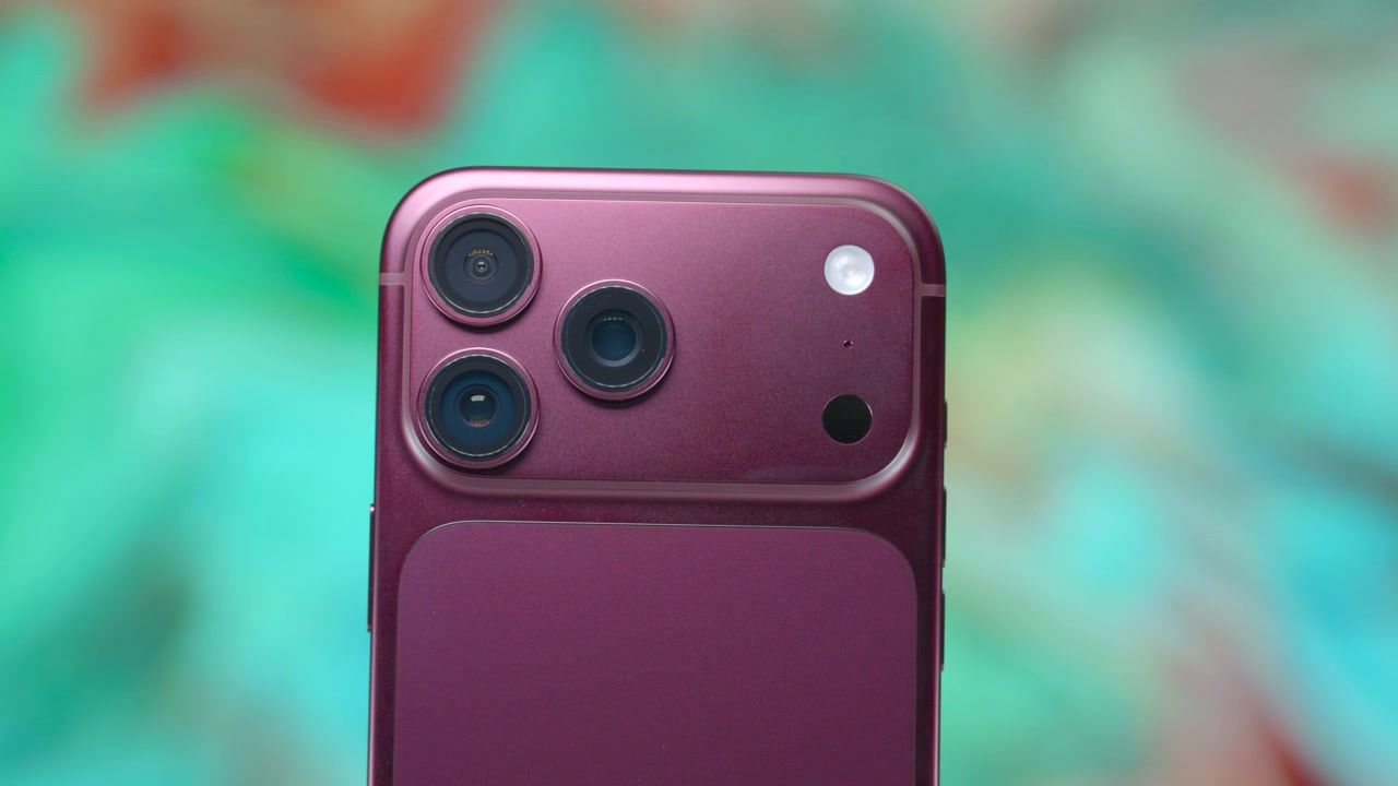 Madryt, Hiszpania, 10 września 2026 r.: iPhone 18 Pro w kolorze ciemnej wiśni powoli obraca się w zbliżeniu, ukazując smukłą metaliczną krawędź, potrójny zestaw aparatów oraz błyszczące wykończenie tylnej obudowy na tle miękko rozmytego gradientu w odcieniach turkusu, różu i koralu