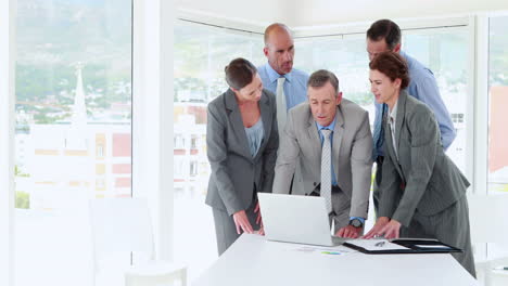 Business-people-looking-at-laptop-computer-during-meeting