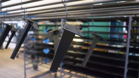 piezas de metal recién recubiertas de polvo colgadas para secar en fábrica