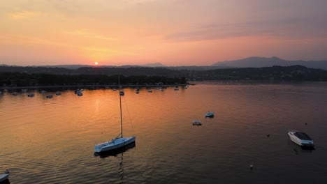 aerial view of idyllic sunset above lago di garda and sato city lombardy italy, serene lakefront and orange sunlight reflection, drone shot