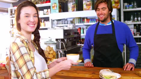 waiter serving a cup of coffee to customer at counter