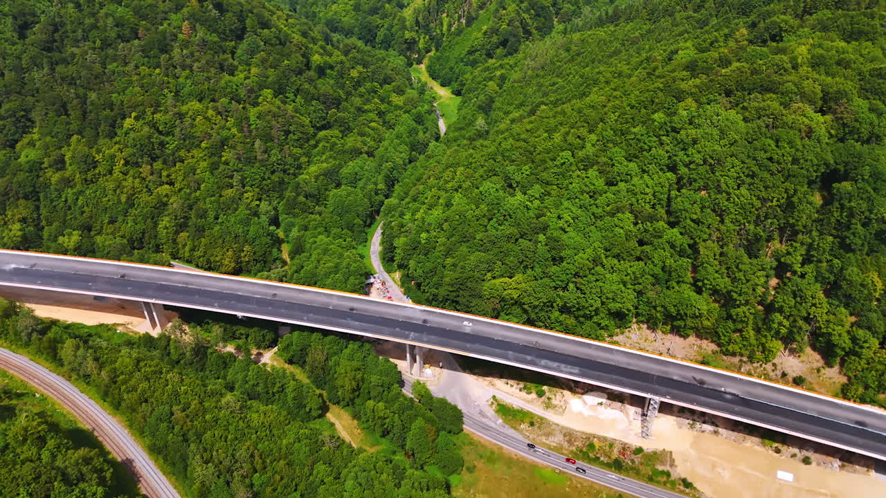 Aerial highway through forest. Elevated view captures a highway winding through lush green trees in a mountainous area, showcasing nature's beauty