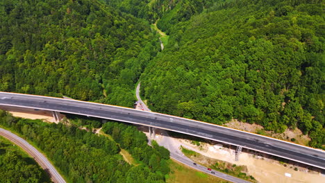 aerial highway through forest. elevated view captures a highway winding through lush green trees in a mountainous area, showcasing nature's beauty