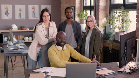 multiethnic team of graphic designers smiling at camera in an animation studio