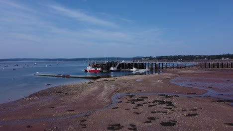 low aerial drone slowly rising over the pier at st-andrews by the sea during low tide in the maritimes, canada